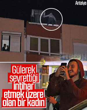 Binanın çatısından sarkan kadını cips yiyerek izlediler