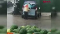 Sağanak yağmur altında araba temizledi