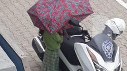 Polisin motosikleti ıslanmasın diye şemsiyesiyle bekledi