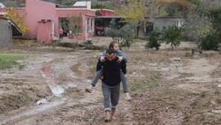 Çocuklarını sırtlarında ana yola kadar taşıyor