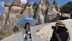Kapadokya'da turistler şemsiye ile geziyor