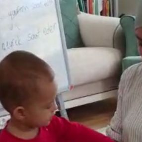 Öğrencilere ders anlatırken çocuğuyla da ilgilenen öğretmen