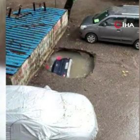 Hindistan’da park halindeki otomobil, su dolu çukura düştü