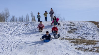 Vanlı çocuklar, kar yağışını plastik bidon kayarak kutluyor