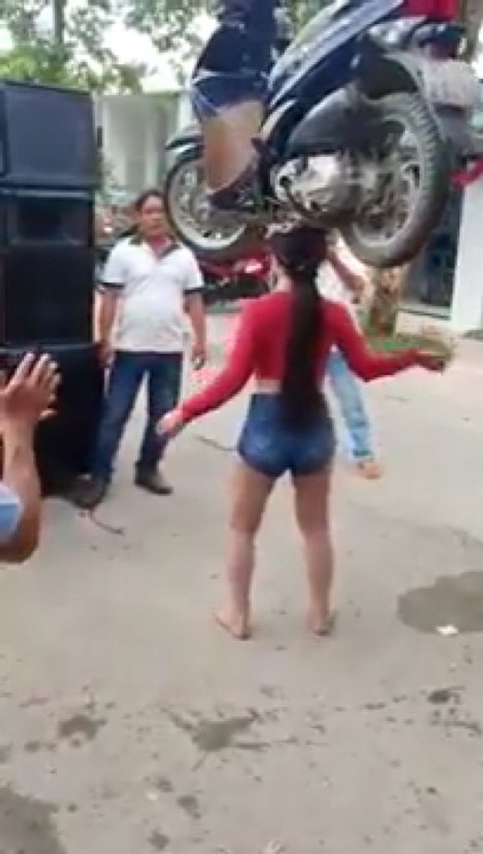 Asyalı genç kadın kafasında scooter taşıdı