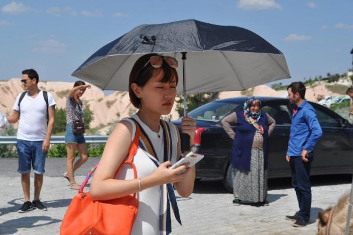 Kapadokya'da turistler şemsiye ile geziyor