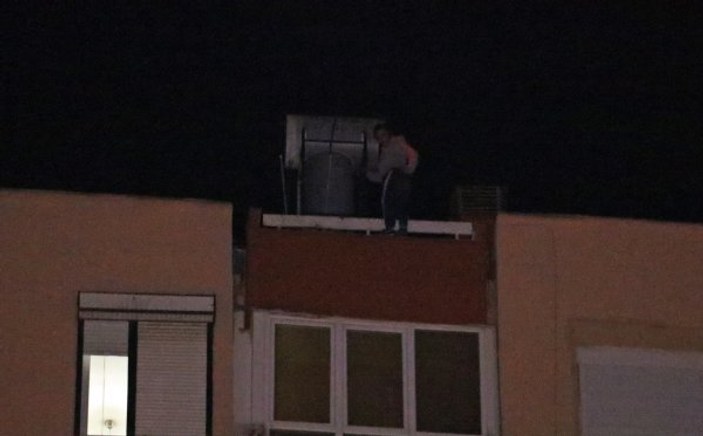 Binanın çatısından sarkan kadını cips yiyerek izlediler