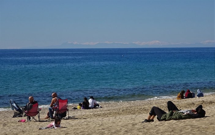 Antalya'da turistler, karlı Toros manzarasıyla denize girdi