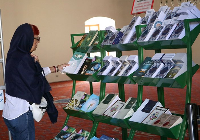 İzmir'de camiyi ziyeret eden turistlere 15 dildeki Kur'an-ı Kerim kitapçıklarını hediye ediyor