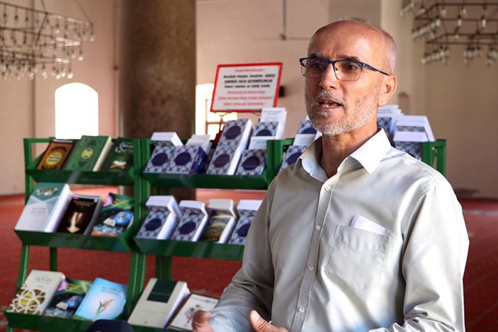İzmir'de camiyi ziyeret eden turistlere 15 dildeki Kur'an-ı Kerim kitapçıklarını hediye ediyor