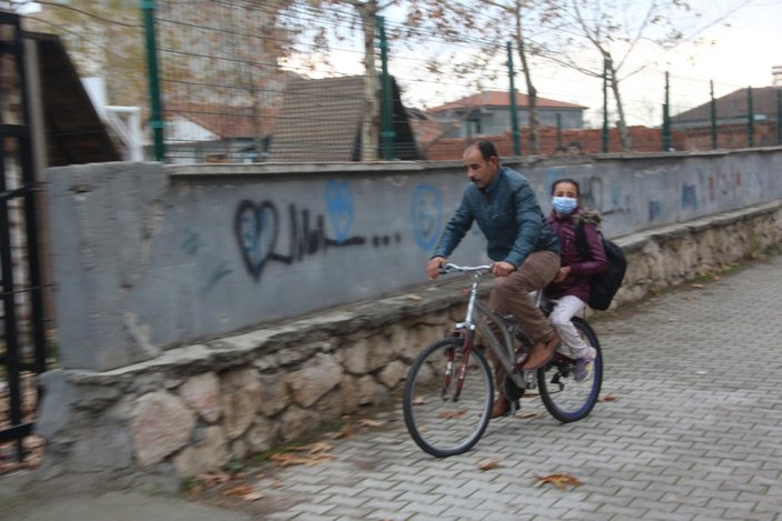 Malatya'daki baba, yürüyemeyen kızını bisikletle okula taşıyor