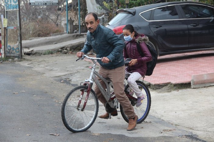 Malatya'daki baba, yürüyemeyen kızını bisikletle okula taşıyor
