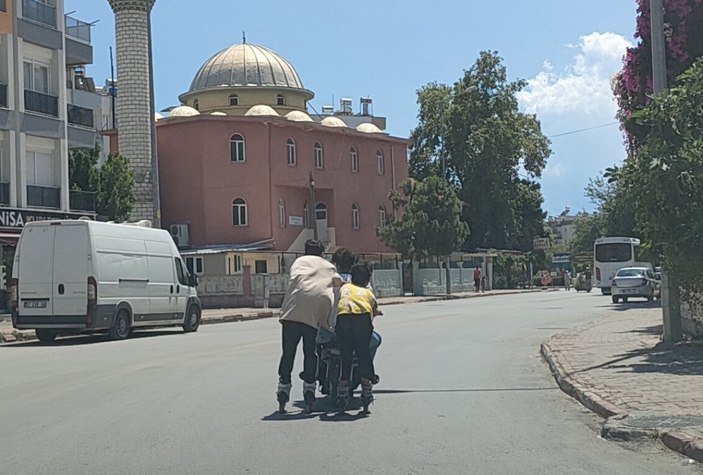 Antalya'da elektrikli bisiklete tutunarak yolculuk yapan patenli çocuklar