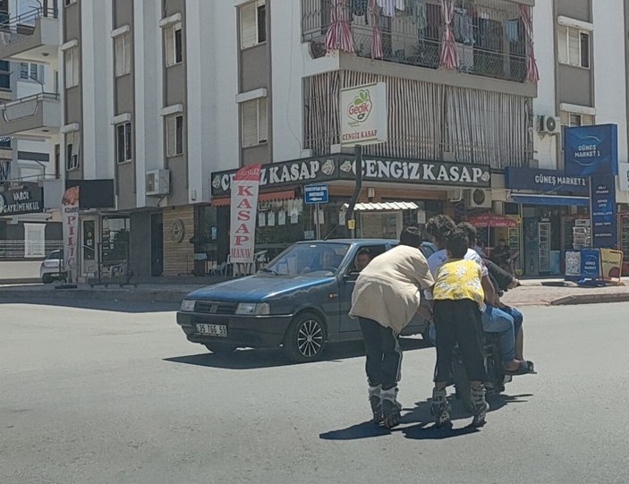 Antalya'da elektrikli bisiklete tutunarak yolculuk yapan patenli çocuklar