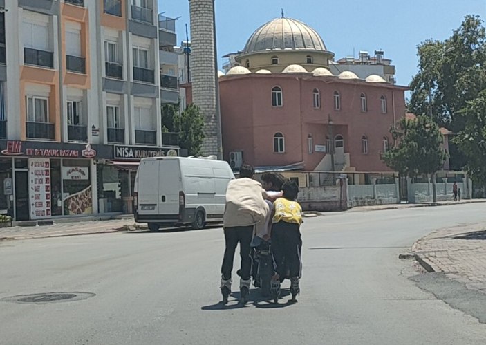 Antalya'da elektrikli bisiklete tutunarak yolculuk yapan patenli çocuklar