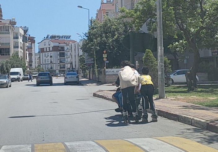 Antalya'da elektrikli bisiklete tutunarak yolculuk yapan patenli çocuklar