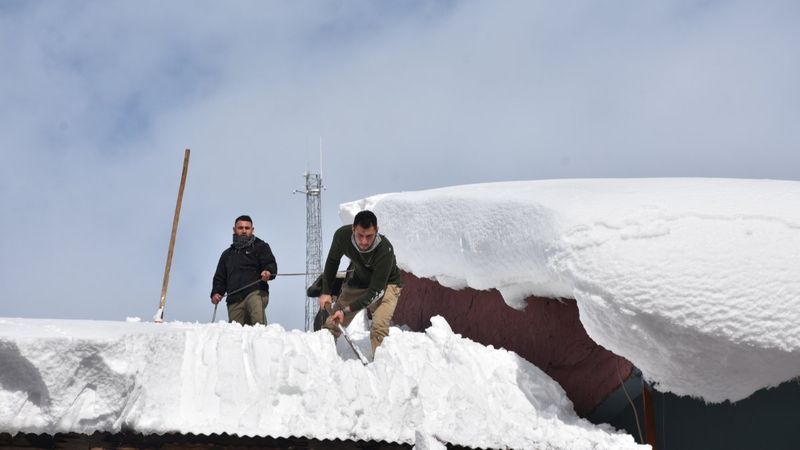 Şırnak'ta bellerine halat bağlayarak çatıdaki karları temizlediler
