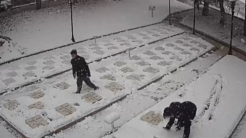 Çanakkale'de 2 genç, beyaza bürünen şehitlikteki mezar taşlarını temizledi