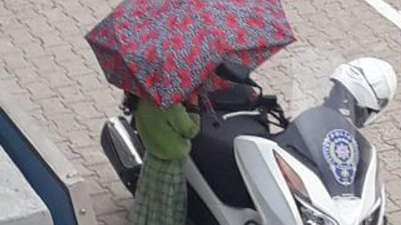 Polisin motosikleti ıslanmasın diye şemsiyesiyle bekledi