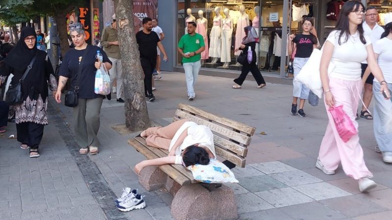 Eskişehir’de sıcaktan bunalan genç yastığını alıp gölgelik bankta uyudu