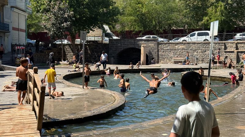 Diyarbakır'da termometreler 40 dereceyi gösterirken çocuklar, süs havuzunda serinliyor