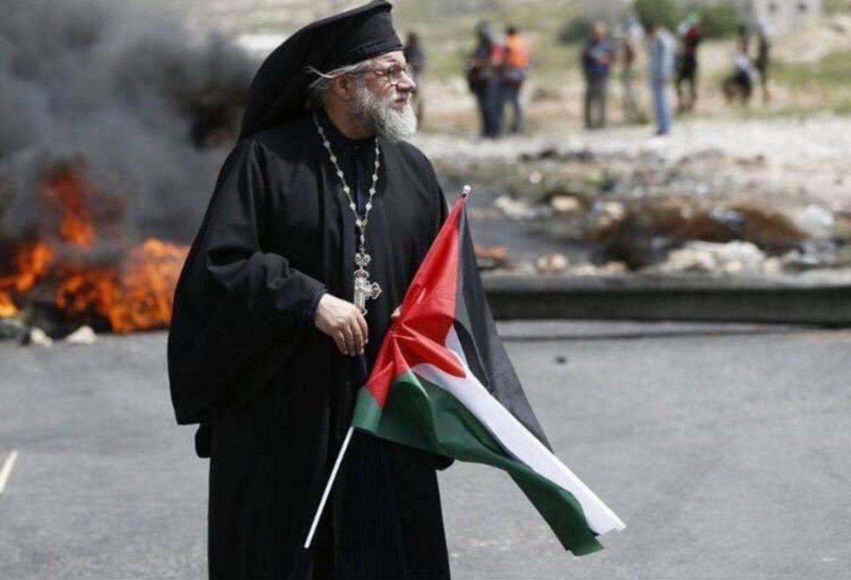 Catholic Archbishop Yulio stands before Israeli soldiers with the Palestinian flag #1